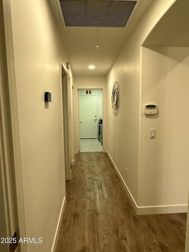 hall with dark wood finished floors, visible vents, and baseboards