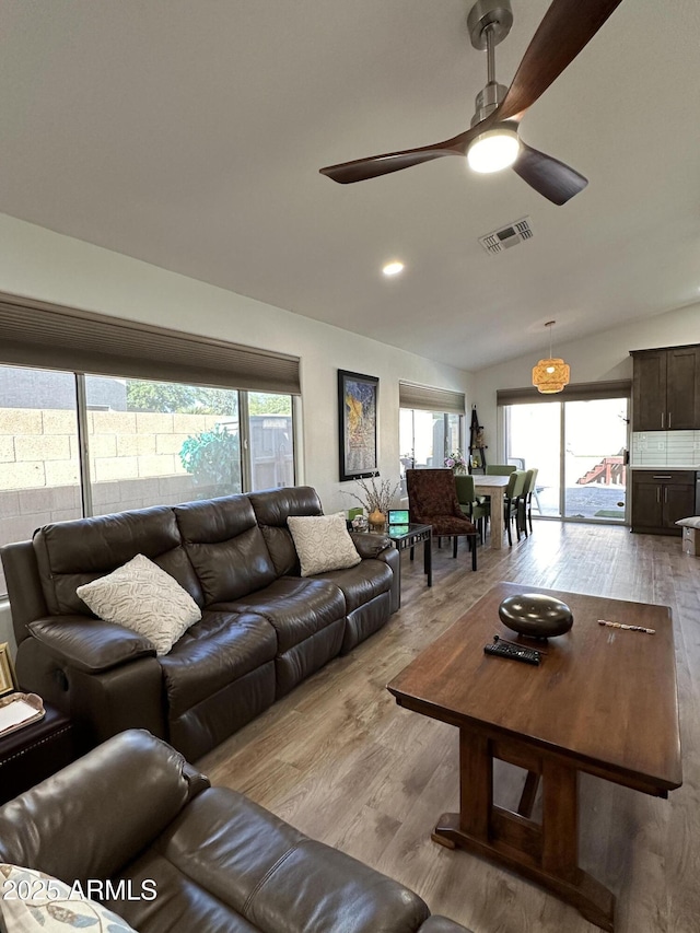 living room featuring lofted ceiling, a ceiling fan, visible vents, and wood finished floors