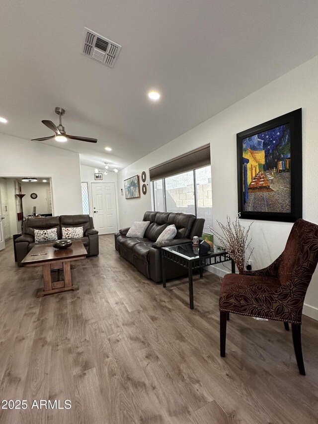 living room with lofted ceiling, wood finished floors, visible vents, and a ceiling fan