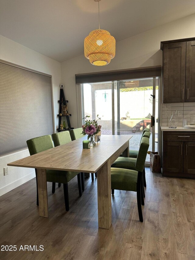 dining space featuring vaulted ceiling, dark wood-style flooring, baseboards, and a healthy amount of sunlight