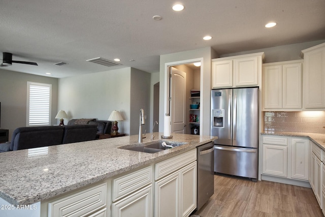 26421 W Zachary Dr, Buckeye, AZ 85396 - kitchen featuring light stone counters, open floor plan, light wood-style floors, appliances with stainless steel finishes, and a sink