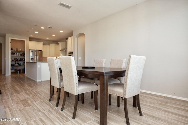 26421 W Zachary Dr, Buckeye, AZ 85396 - dining space with baseboards, wood finish floors, recessed lighting, visible vents, and arched walkways