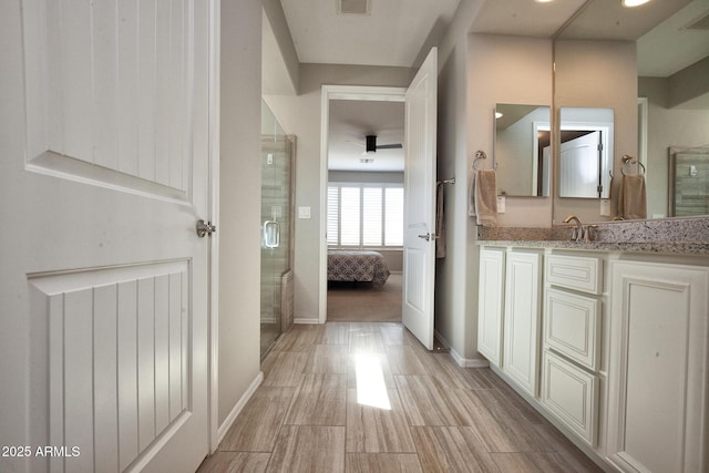 26421 W Zachary Dr, Buckeye, AZ 85396 - ensuite bathroom featuring connected bathroom, vanity, wood finished floors, a stall shower, and baseboards