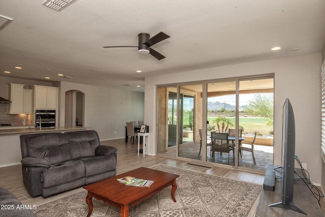 26421 W Zachary Dr, Buckeye, AZ 85396 - living room featuring ceiling fan, arched walkways, and light wood-style floors