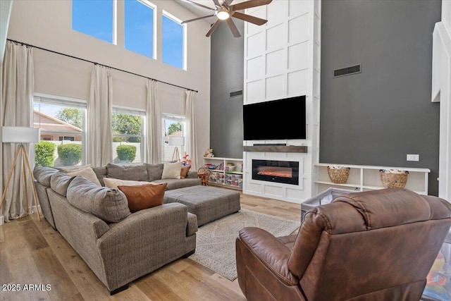 2466 E Harrison Ct, Gilbert, AZ 85295 - living area featuring a high ceiling, ceiling fan, healthy amount of natural light, light wood-type flooring, and a glass covered fireplace