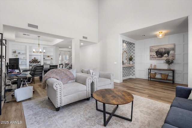 2466 E Harrison Ct, Gilbert, AZ 85295 - living room with wood finished floors, a chandelier, baseboards, and a tray ceiling