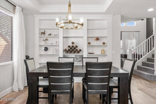2466 E Harrison Ct, Gilbert, AZ 85295 - dining space featuring a chandelier, light wood-style flooring, stairway, baseboards, and built in shelves