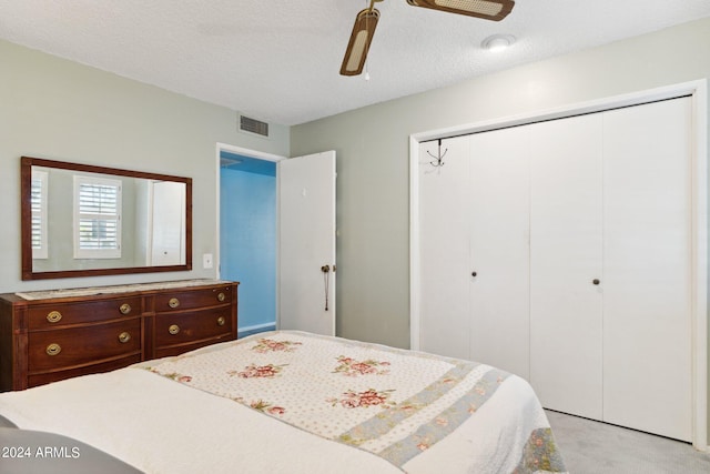 bedroom with a textured ceiling, ceiling fan, and light colored carpet