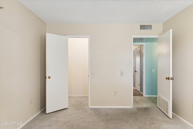 unfurnished bedroom featuring a textured ceiling and light carpet