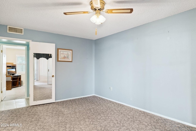 unfurnished room with light carpet, ceiling fan, and a textured ceiling