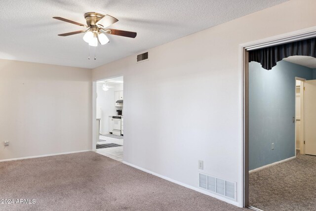 carpeted spare room with ceiling fan and a textured ceiling