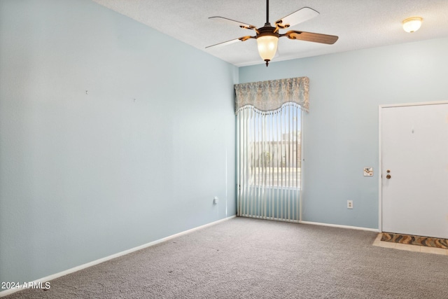 carpeted spare room featuring ceiling fan and a textured ceiling