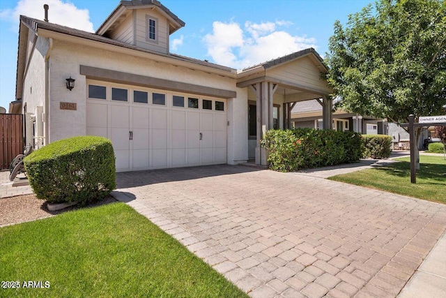 single story home with a front lawn, decorative driveway, an attached garage, and stucco siding