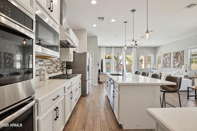 kitchen featuring visible vents, a kitchen bar, open floor plan, and a sink