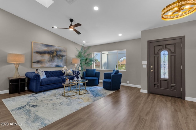 living room featuring wood-type flooring, ceiling fan, and vaulted ceiling with skylight