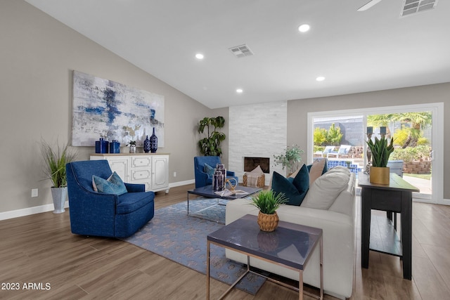 living room with a stone fireplace, hardwood / wood-style floors, and lofted ceiling