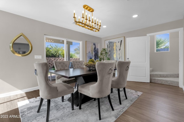 dining space featuring a healthy amount of sunlight, light wood-type flooring, and a notable chandelier