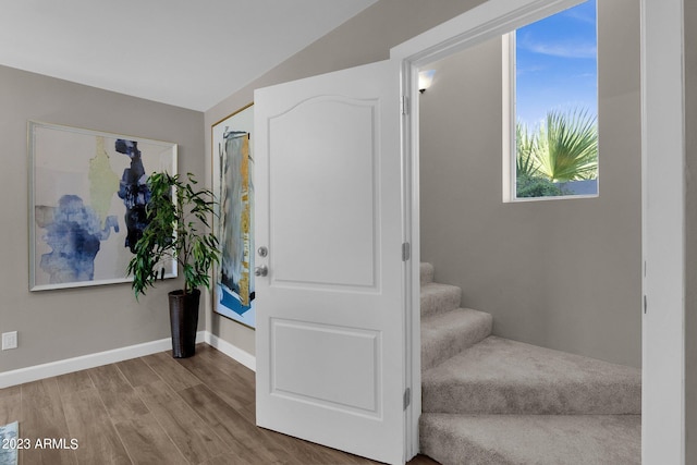 foyer entrance with wood-type flooring and vaulted ceiling