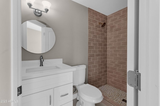 bathroom with vanity, toilet, and a tile shower