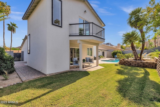 back of property with a fenced in pool, a patio area, a yard, and a balcony