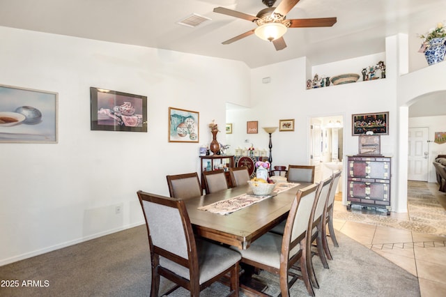 dining area featuring a ceiling fan, visible vents, arched walkways, lofted ceiling, and light tile patterned flooring