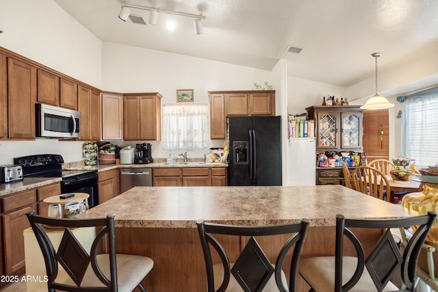 kitchen featuring visible vents, a breakfast bar, black appliances, and lofted ceiling