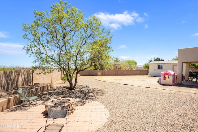 view of yard featuring a fenced backyard, a fire pit, and a patio area