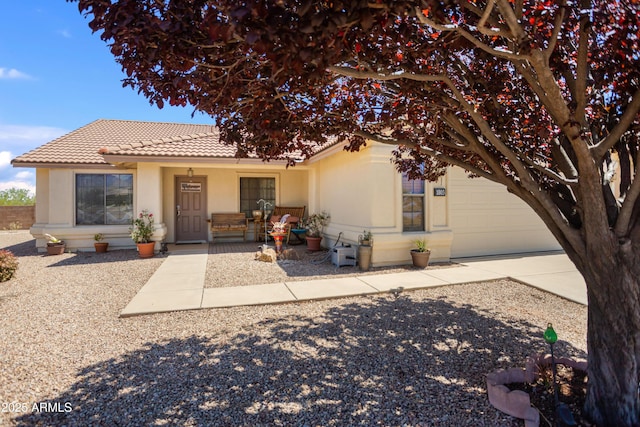 view of front of home with a garage, stucco siding, covered porch, a tiled roof, and driveway