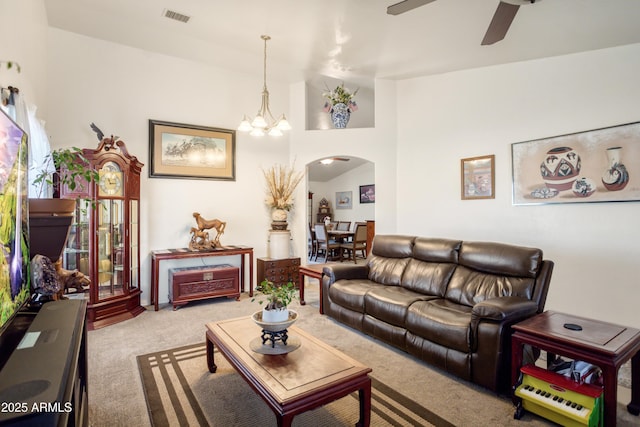 carpeted living area featuring arched walkways, ceiling fan with notable chandelier, lofted ceiling, and visible vents