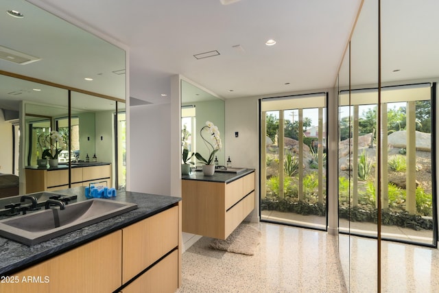 bathroom featuring a sink, speckled floor, and two vanities