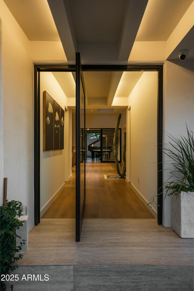 hall with baseboards and wood finished floors