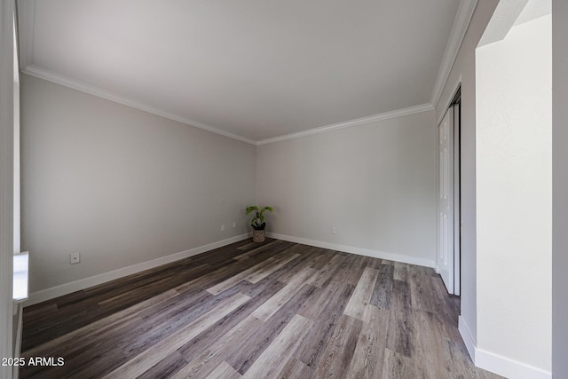 spare room with crown molding, baseboards, and wood finished floors