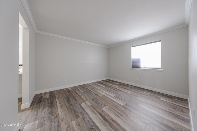 spare room with baseboards, crown molding, and wood finished floors