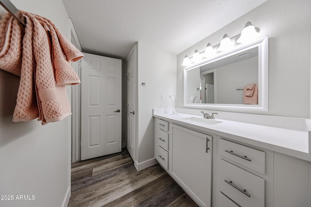 bathroom featuring baseboards, wood finished floors, and vanity