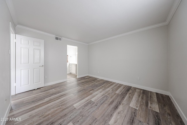unfurnished room with baseboards, wood finished floors, and visible vents