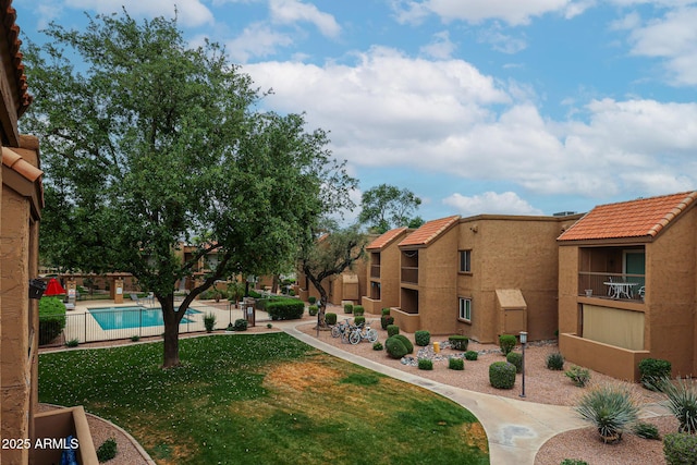view of community with a swimming pool, fence, and a lawn