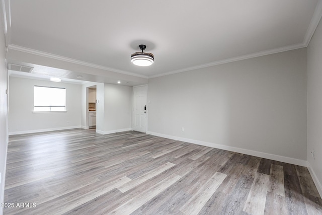 spare room featuring baseboards, crown molding, and wood finished floors