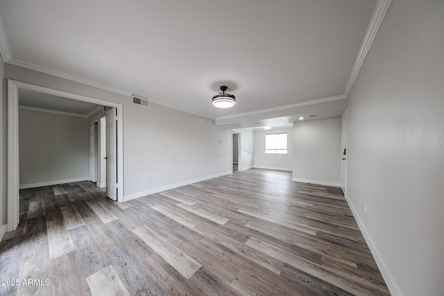 unfurnished room with visible vents, ornamental molding, baseboards, and wood finished floors