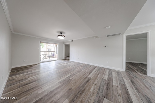 spare room with crown molding, wood finished floors, baseboards, and visible vents