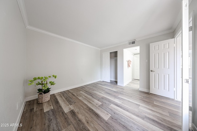 unfurnished bedroom featuring light wood-style floors, visible vents, baseboards, and ornamental molding