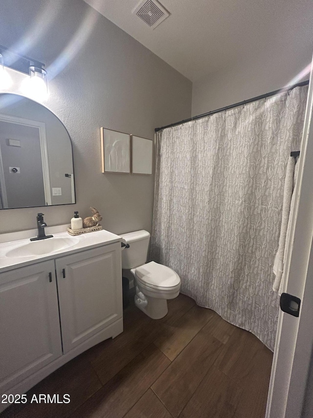 bathroom featuring visible vents, toilet, vanity, and wood finished floors