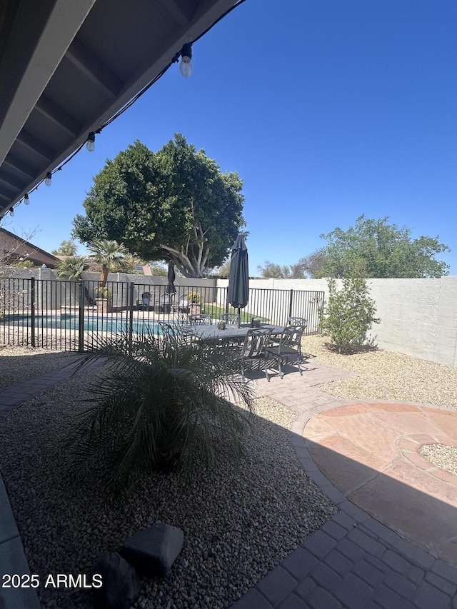 view of patio with outdoor dining area, a fenced backyard, and a fenced in pool