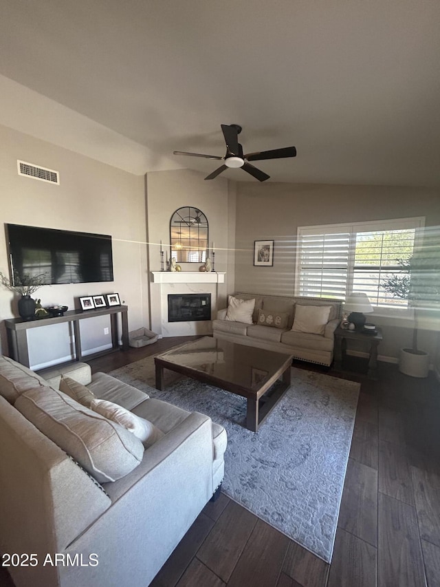 living room with a glass covered fireplace, vaulted ceiling, dark wood-style floors, and visible vents