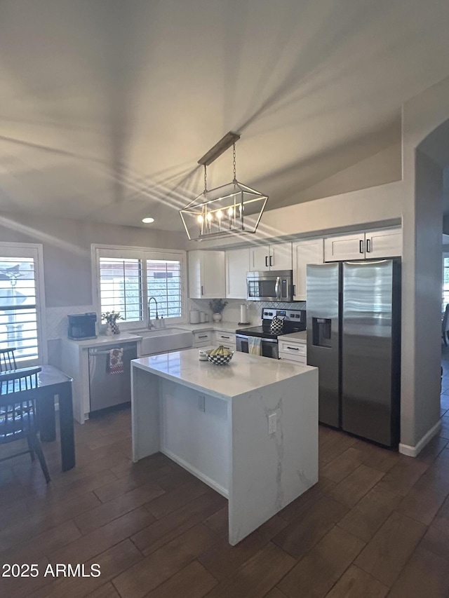 kitchen with dark wood-type flooring, a sink, a kitchen island, appliances with stainless steel finishes, and white cabinets