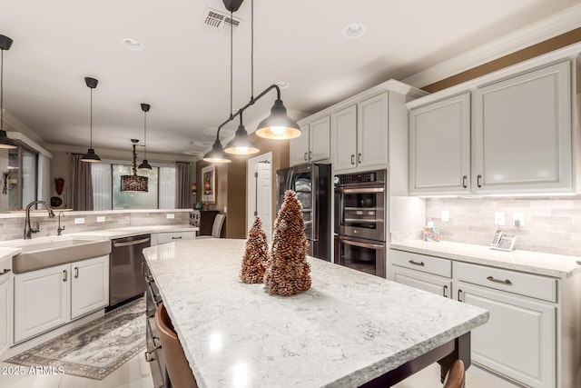 kitchen featuring decorative light fixtures, a center island, sink, and stainless steel appliances