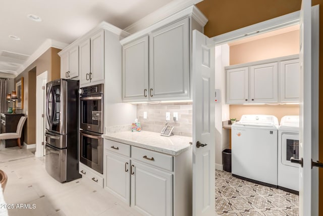 kitchen featuring white cabinetry, separate washer and dryer, light stone counters, crown molding, and appliances with stainless steel finishes