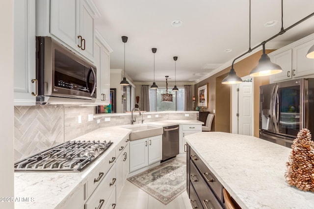 kitchen featuring backsplash, white cabinets, hanging light fixtures, and appliances with stainless steel finishes