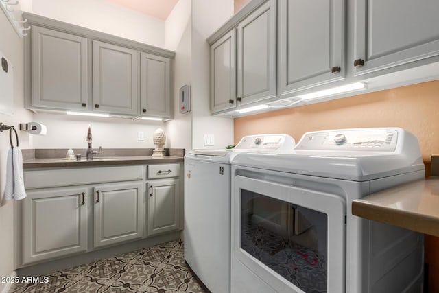 laundry area with washer and clothes dryer, light tile patterned flooring, cabinets, and sink