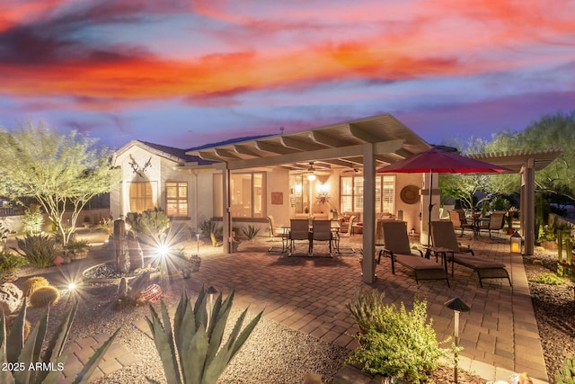 back house at dusk with a patio area and a pergola