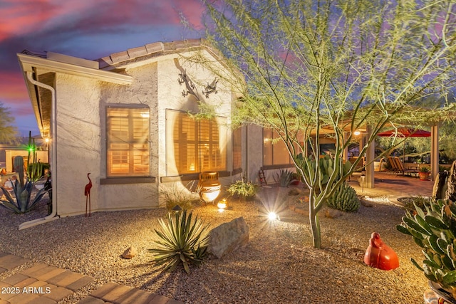 property exterior at dusk with a patio area